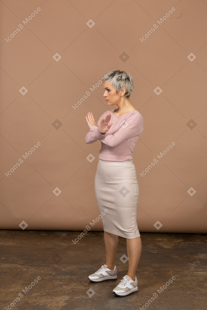 Side view of a woman in casual clothes showing stop gesture