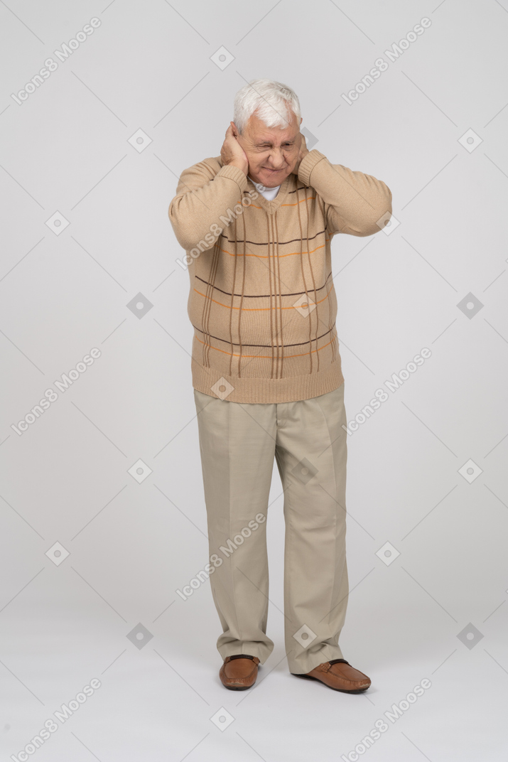 Vista frontal de un anciano que cubre las orejas con las manos