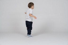 Rear view of a boy standing with his arms bent