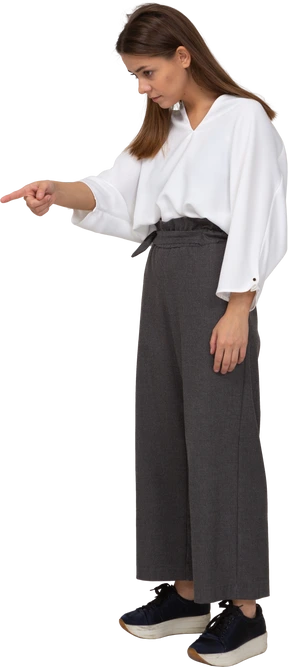 Three-quarter view of a young lady in office clothing pointing finger