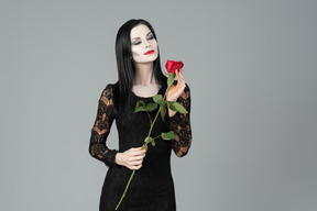 Morticia addams smelling red rose
