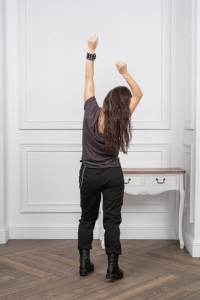 Back view of an unrecognizable female raising her hands