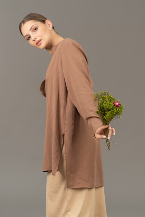 Jeune femme avec des fleurs de prairie regardant la caméra