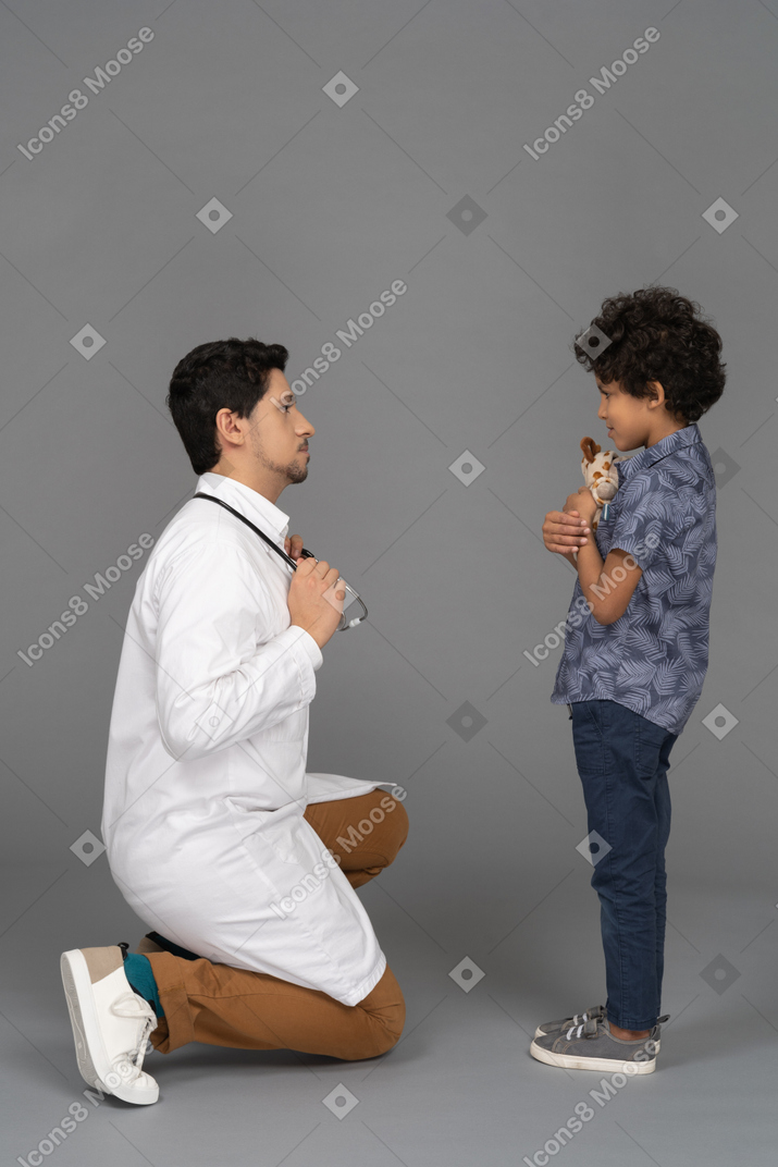 Niño sosteniendo un juguete mientras el doctor lo mira