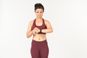 Indian girl in sporstwear checking fitness tracker