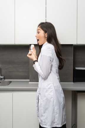 Side view of a surprised female dentist holding a jaws prototype and looking aside