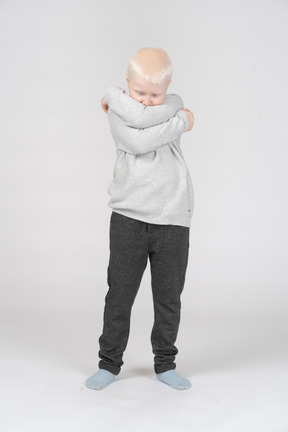 Little boy hugging himself