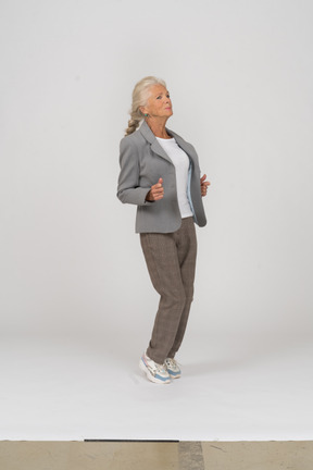 Side view of an old lady in suit standing on toes