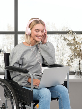 A woman sitting in a wheel chair using a laptop computer