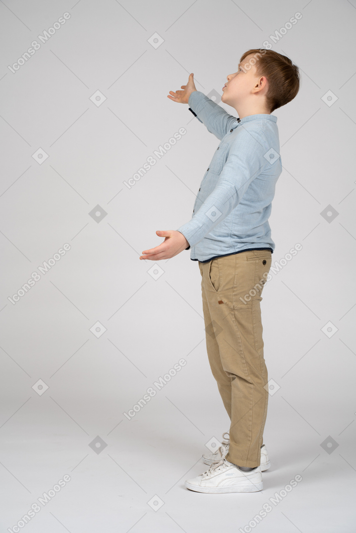 Side view of a boy with outstretched arms looking up