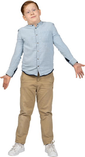 Front view of a confused boy standing with outstretched arms and looking at camera