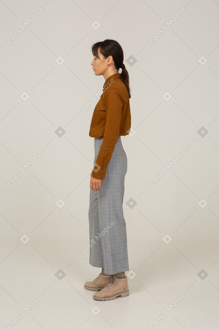 Vue latérale d'une jeune femme asiatique en culotte et chemisier debout immobile les yeux fermés