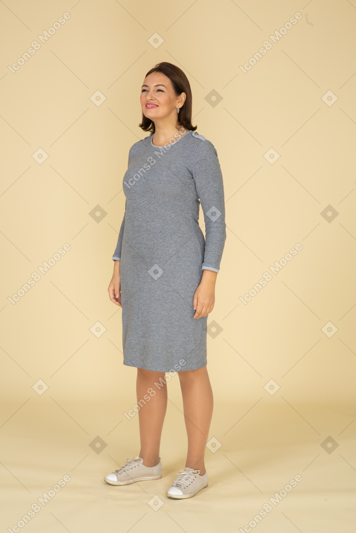 프로필에 서 있는 회색 드레스를 입은 여자