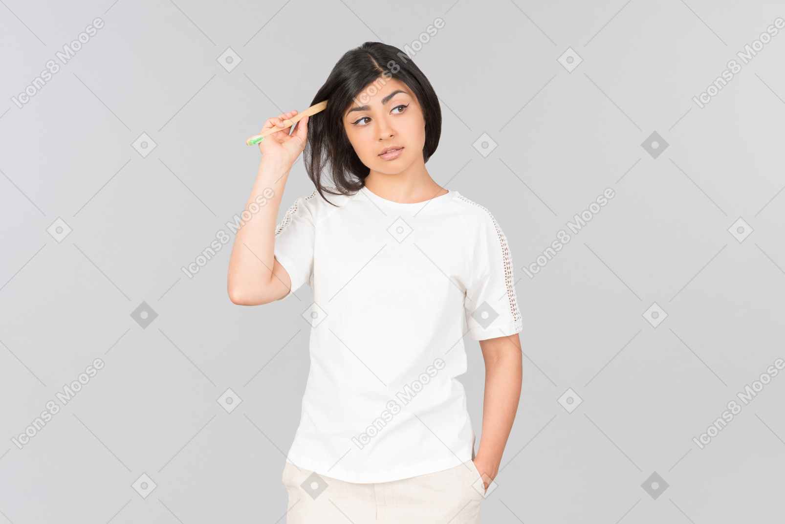 Pensive young indian woman touching hair with a toothbrush