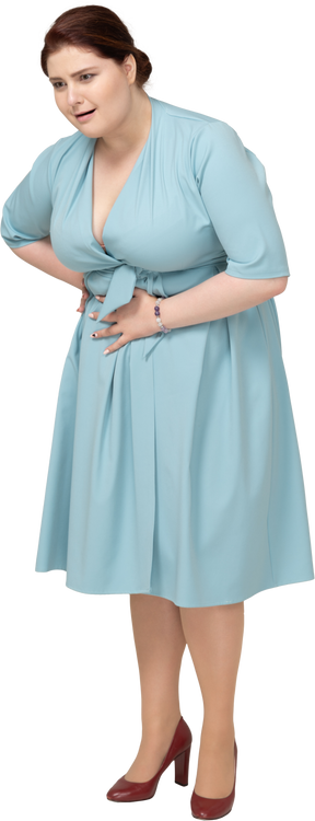Front view of a woman in blue dress suffering from stomachache