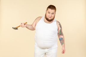 Emotional young big guy holding hammer