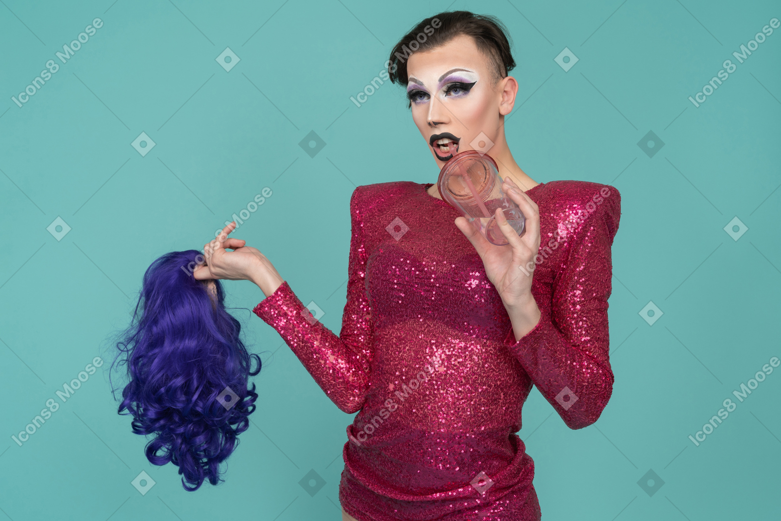 Close-up of a drag queen in pink dress drinking through straw & holding wig