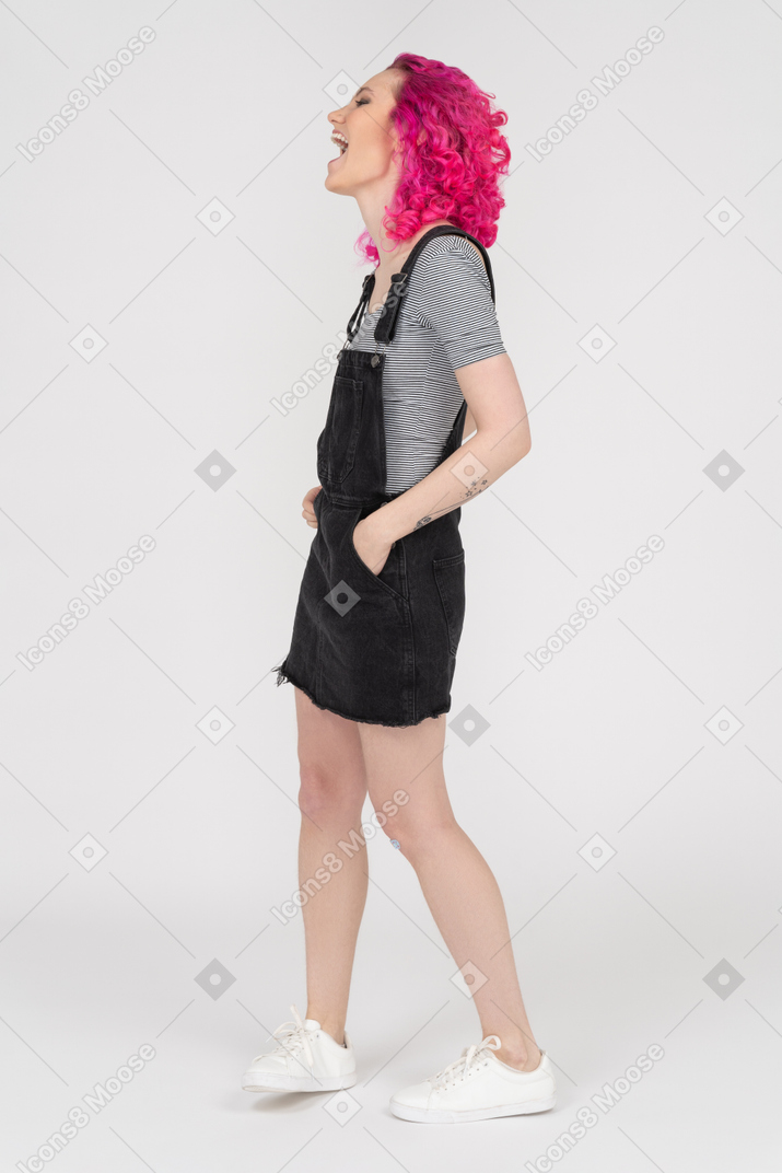Mujer con cabello rosado rizado riendo de perfil