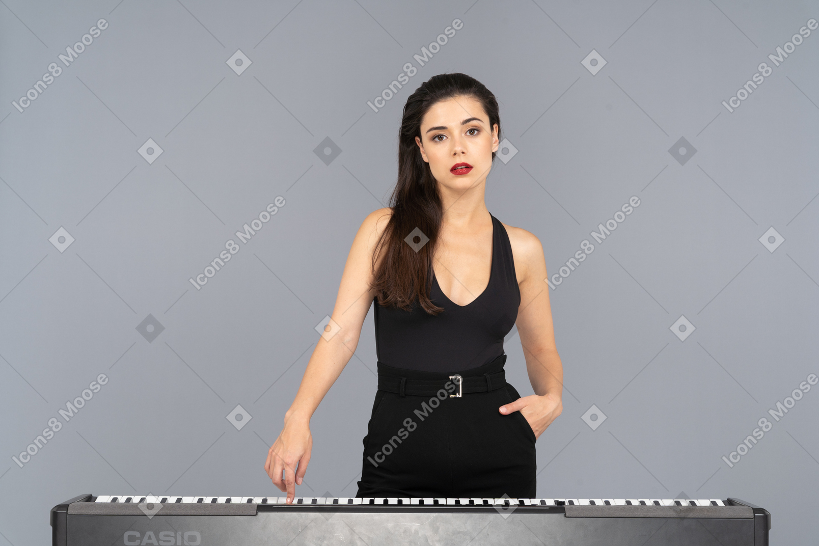 Vista frontale di una giovane donna in abito nero premendo il tasto di un pianoforte