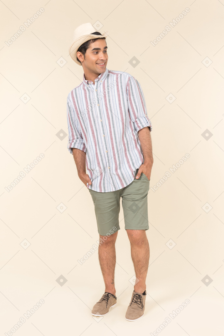 Young caucasian guy in hat holding hands in pockets
