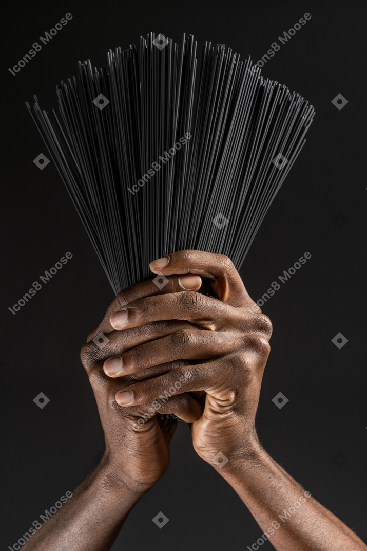 Close-up human hands holding black pasta in the dark