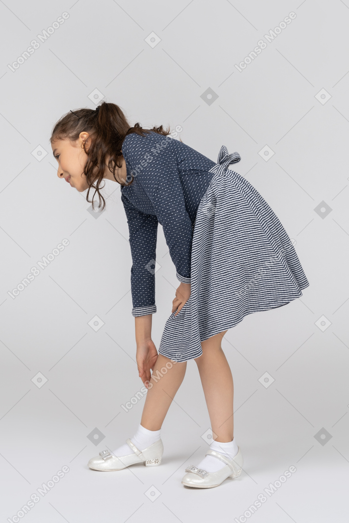 Side view of a girl bending over to reach her leg
