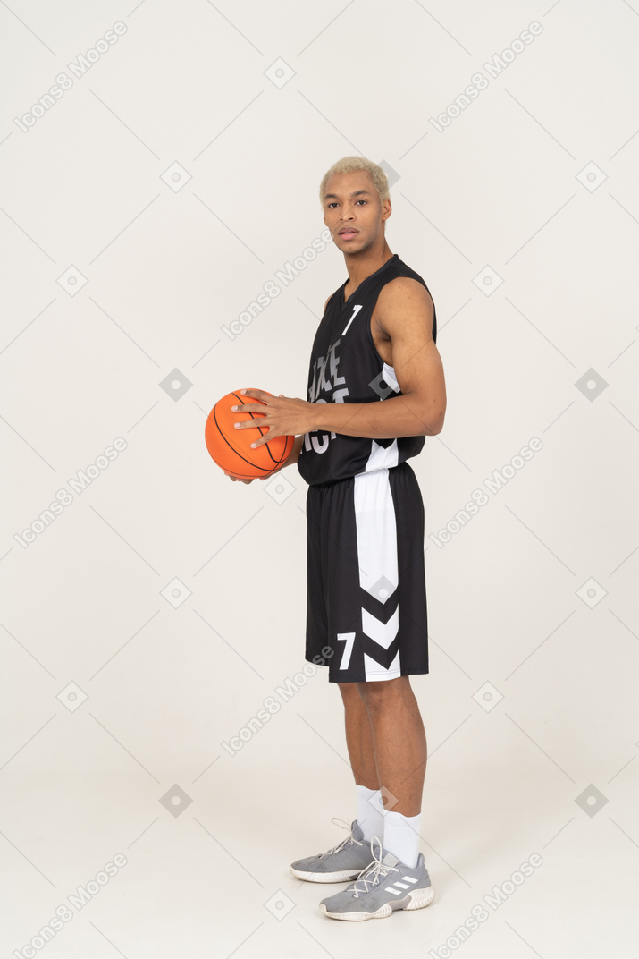 Seitenansicht eines jungen männlichen basketballspielers, der einen ball hält