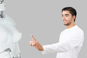 A caucasian bearded man wants to touch a robot woman
