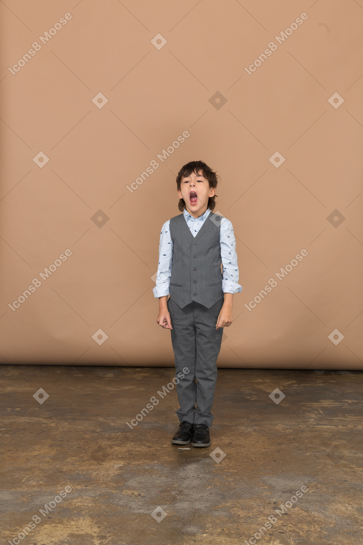 Front view of a boy in suit looking at camera and yawning