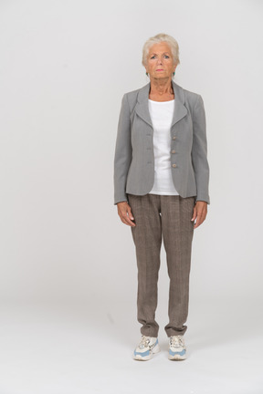 Vue de face d'une vieille femme en veste grise regardant la caméra