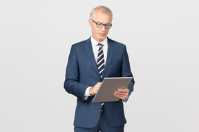 Homem de negócios elegante de meia-idade, usando seu tablet