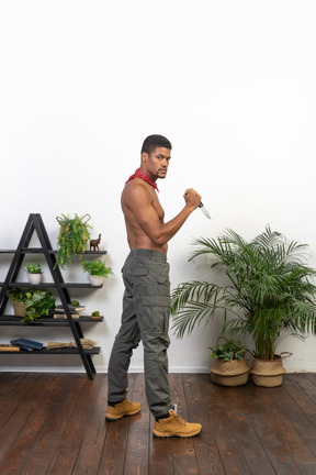 Side view of strong man with knife looking at camera