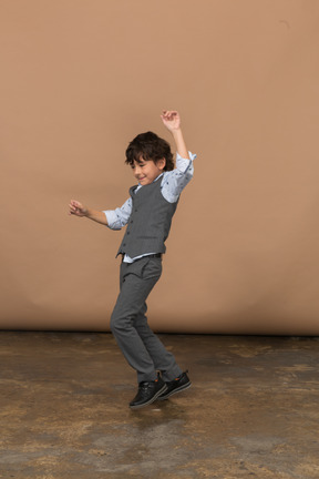 Вид сбоку на танцующего мальчика в костюме