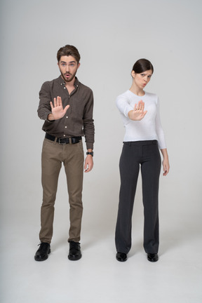 Vista frontal de um jovem casal com roupas de escritório estendendo a mão