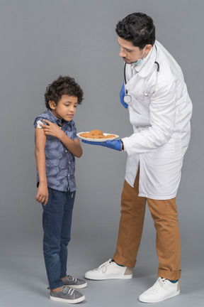 Médico dando biscoitos para menino