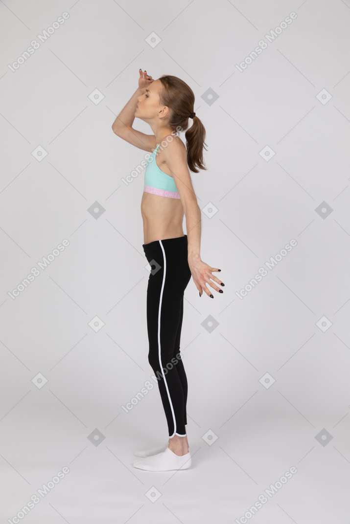 Вид сбоку на девушку-подростка в спортивной одежде, смотрящую вдаль