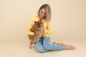 Niña sentada y sosteniendo un perro spitz