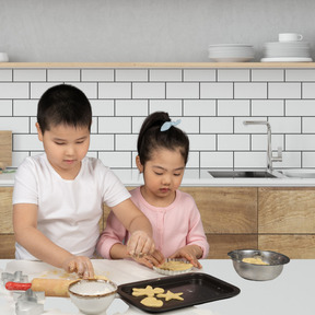 Two children are making cookies in a kitchen