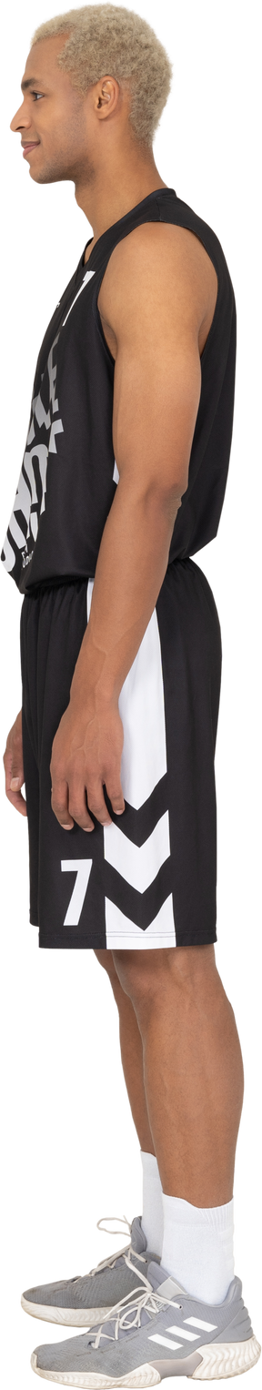 Vue latérale d'un jeune joueur de basket-ball masculin debout immobile