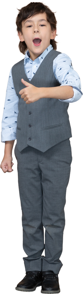 Vista frontal de un niño con traje gris que muestra el pulgar hacia arriba