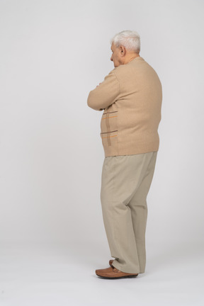 Vue latérale d'un vieil homme en vêtements décontractés debout avec les bras croisés