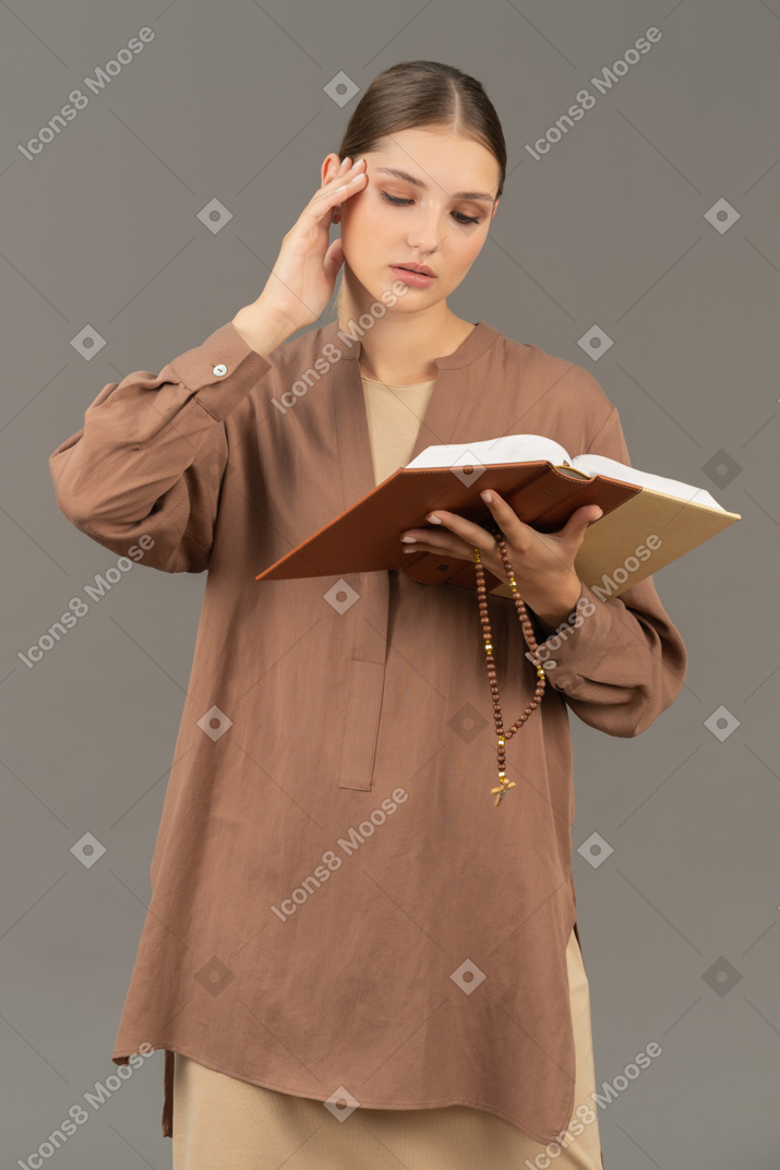 Young woman touching her temple while reading book