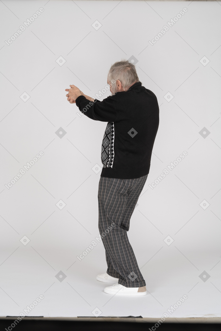 Rear view of old man shooting with finger gun