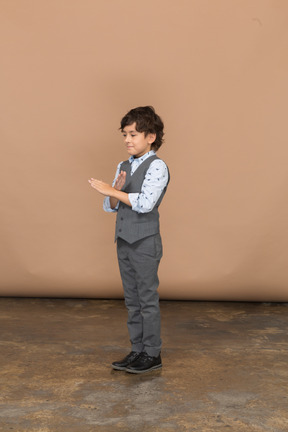 Vista lateral de un niño con traje gris que muestra un gesto de parada