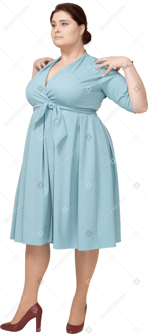 Front view of a woman in blue dress standing with hands on shoulders