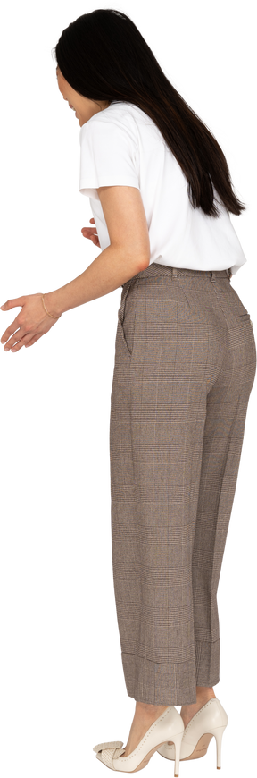 Vista posteriore di tre quarti di una giovane donna gesticolante in calzoni e maglietta