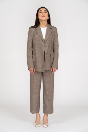 Front view of a young lady in brown business suit looking at camera while raising head