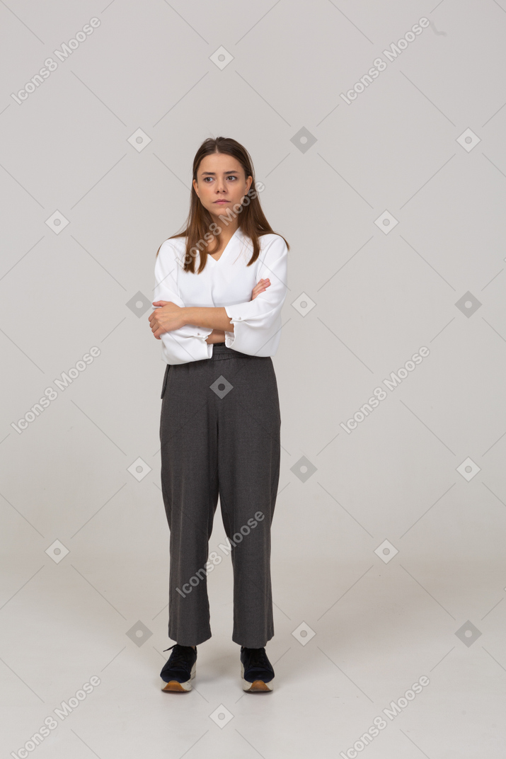 Front view of a doubtful young lady in office clothing crossing arms