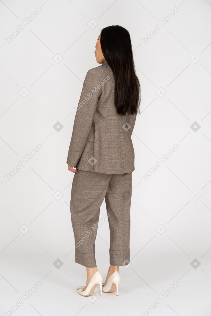 茶色のビジネススーツで驚いた若い女性の4分の3の背面図