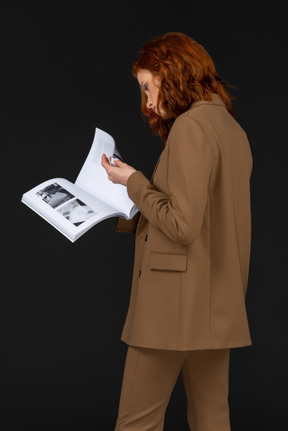 Woman in brown suit flipping through magazine